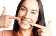 Woman pointing at beautiful smile after laser contouring to treat gummy smile.